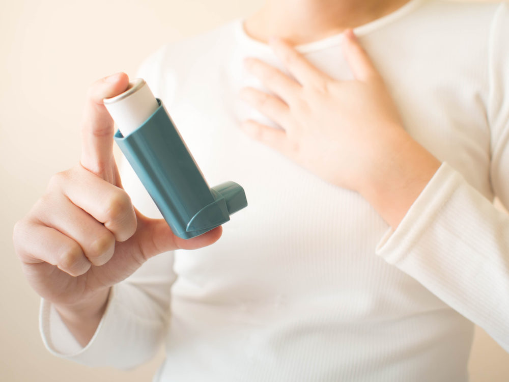 Child clutching chest and holding an asthma inhaler