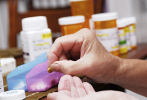 A hand adding pills to a pill box