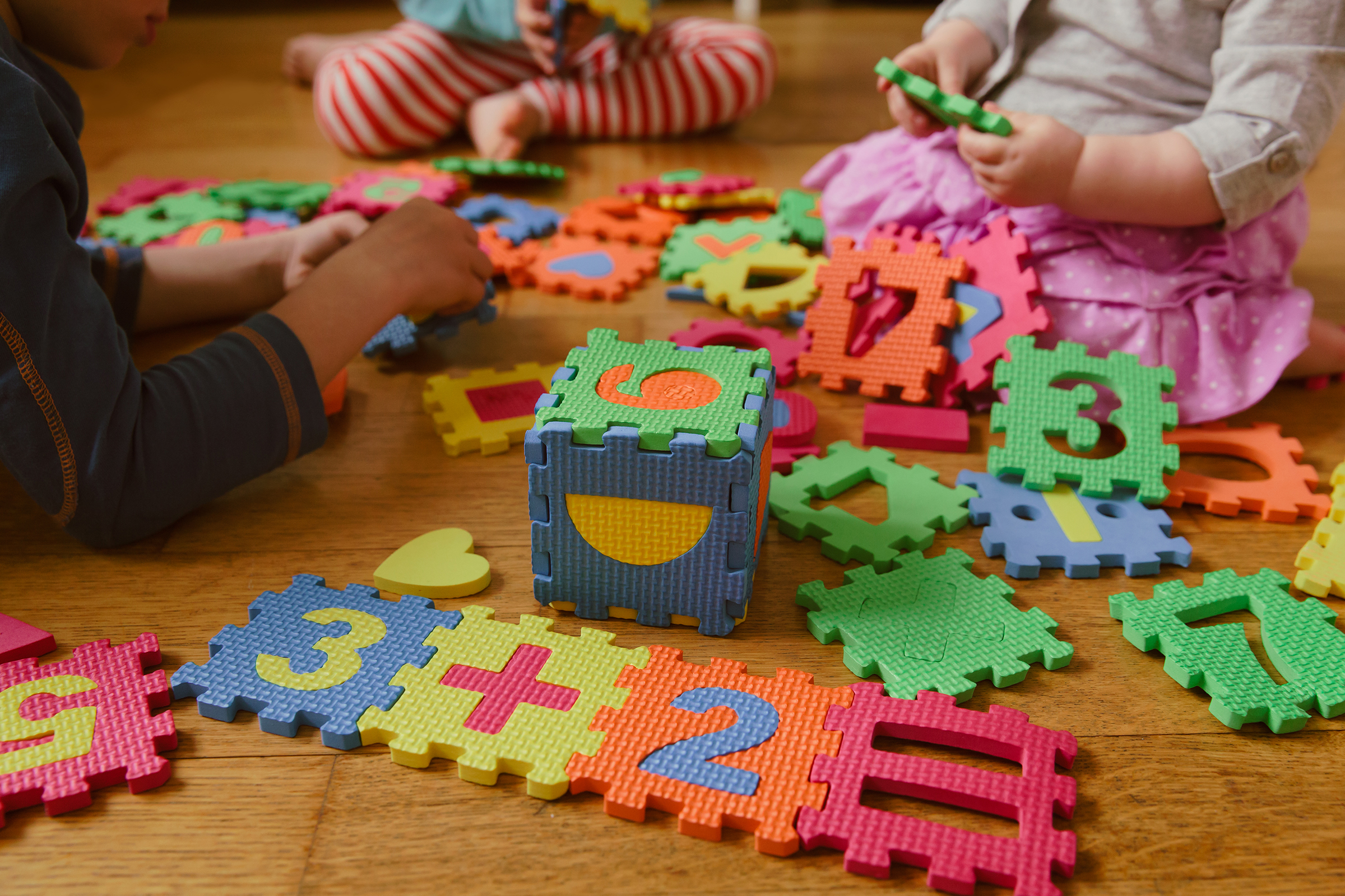 children playing together on the floor with number puzzles