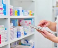 Pharmacist with an electronic tablet device checking stock on pharmacy shelves