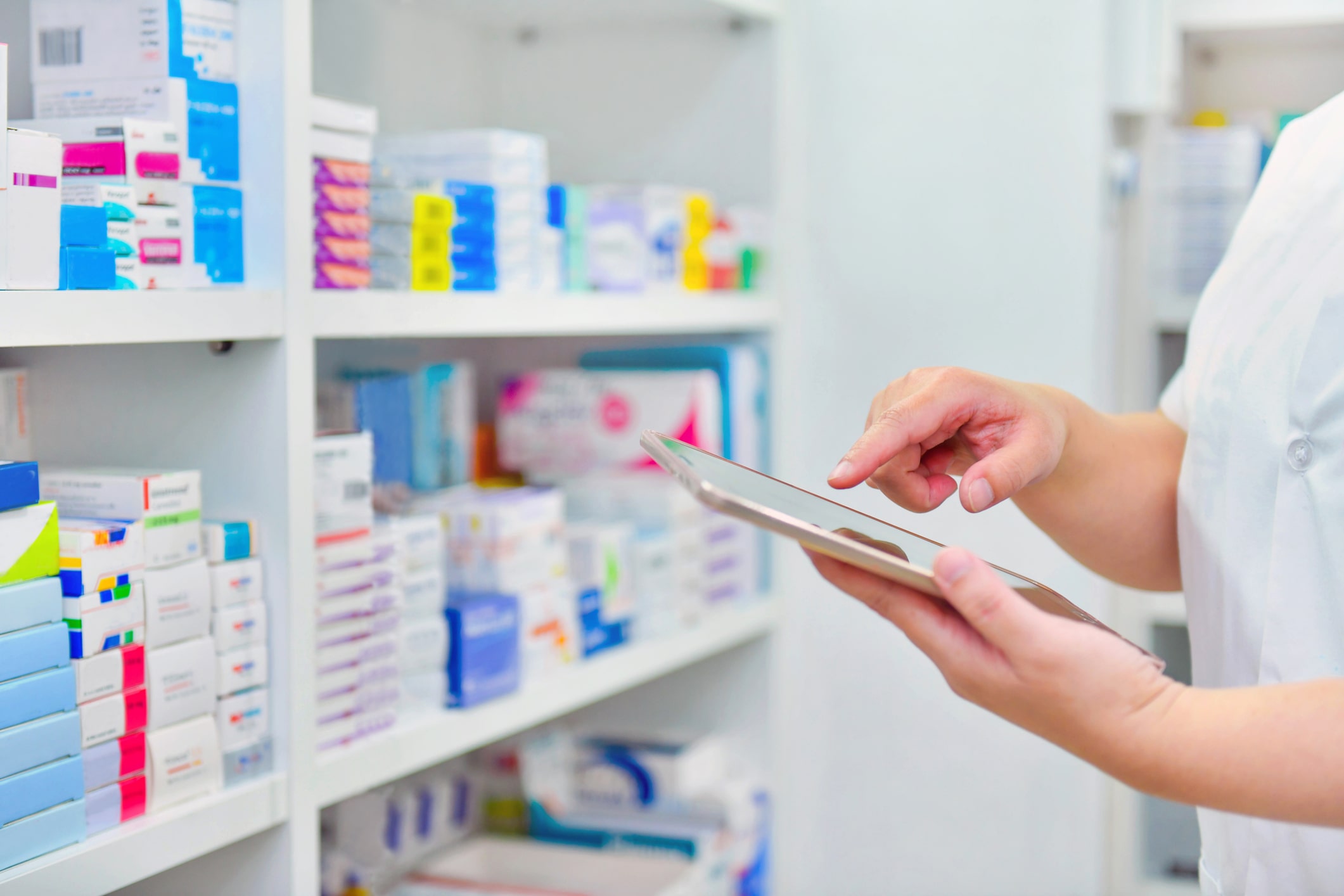 Pharmacist with an electronic tablet device checking stock on pharmacy shelves