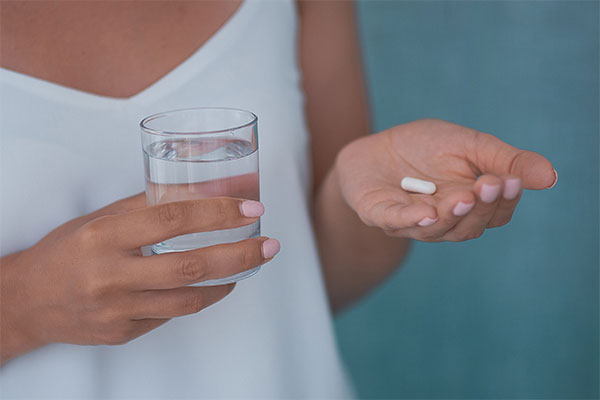 woman holding a zantac ranitidine pill with a glass of water