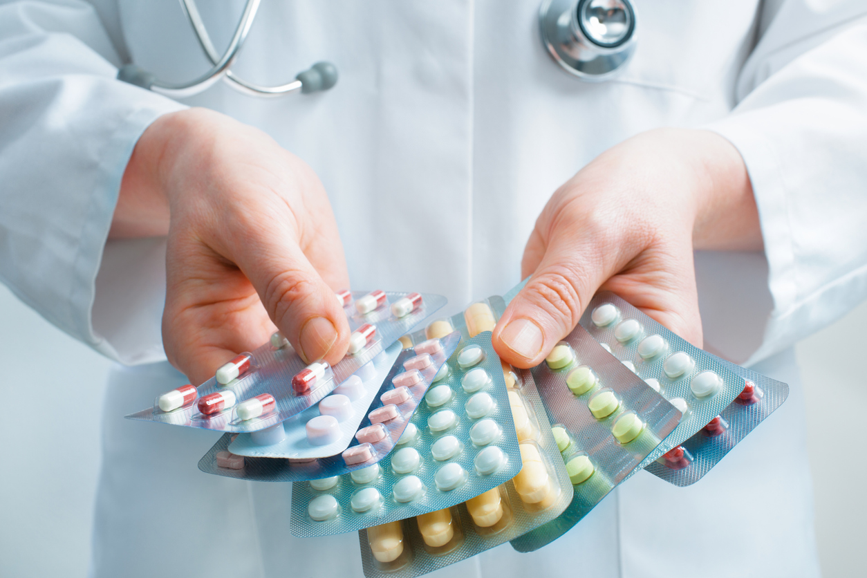 Doctor holding out several packs of a variety of pills