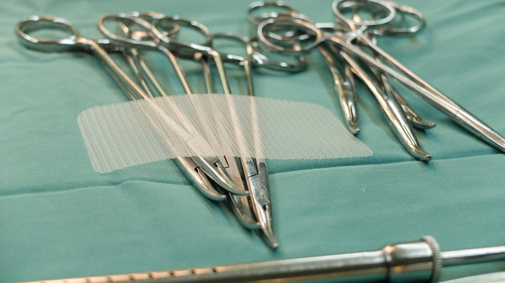 non absorbable synthetic hernia mesh laying on a surgeon's tray of forceps