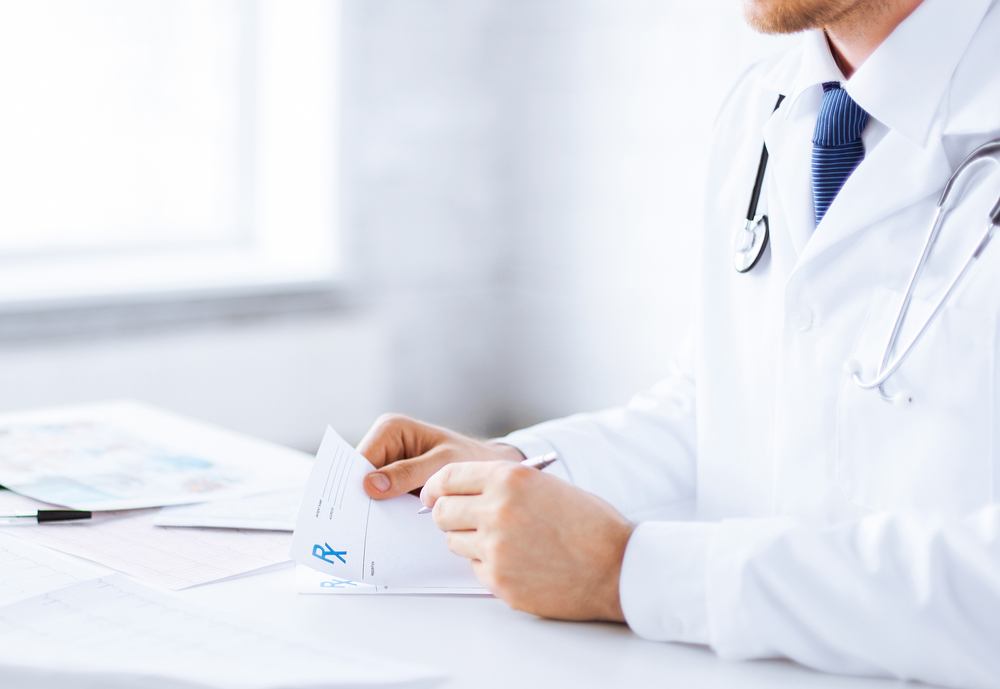 close up of male doctor writing prescription