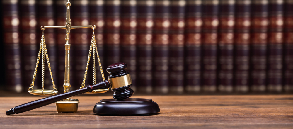 Wooden gavel with scales of justice and law books on a wooden desk