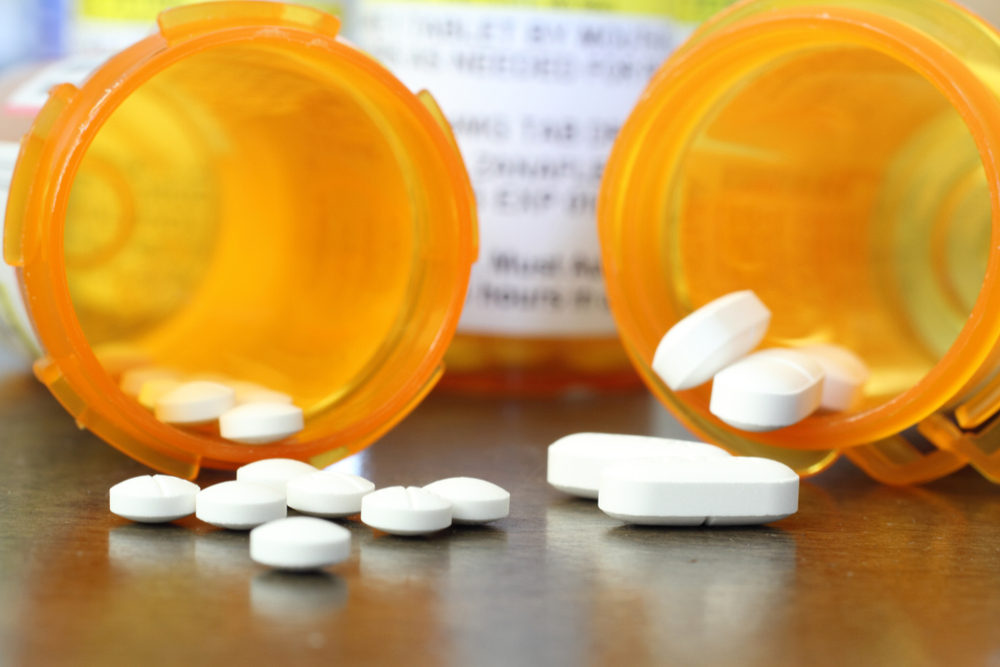 Opioid prescription pain pills from medicine bottles on a table inside a home.