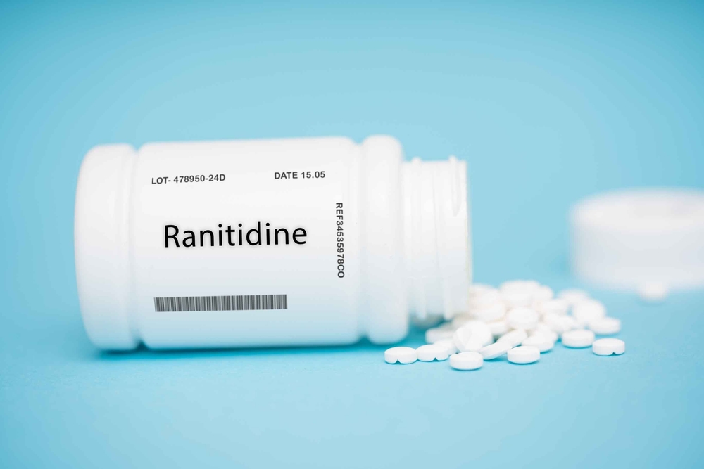 a bottle of ranitidine pills spilled on to blue background