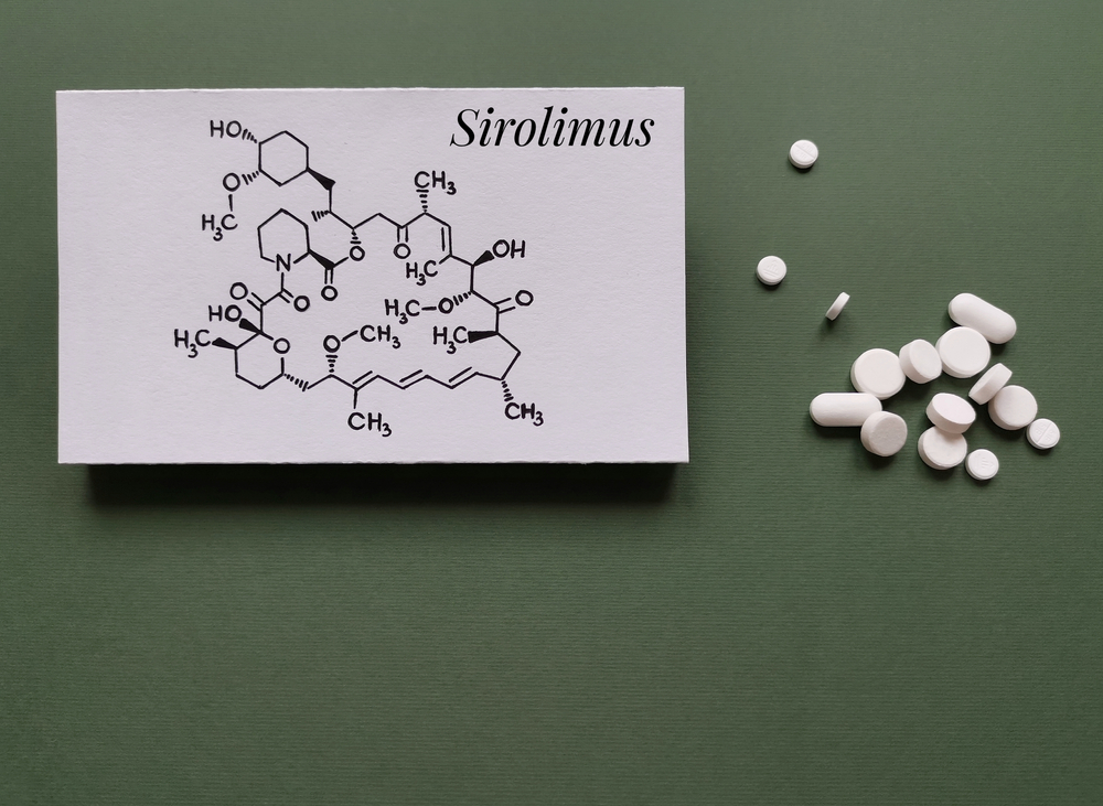 Structural chemical formula of sirolimus molecule with white rapamune tablets and pills on a green background