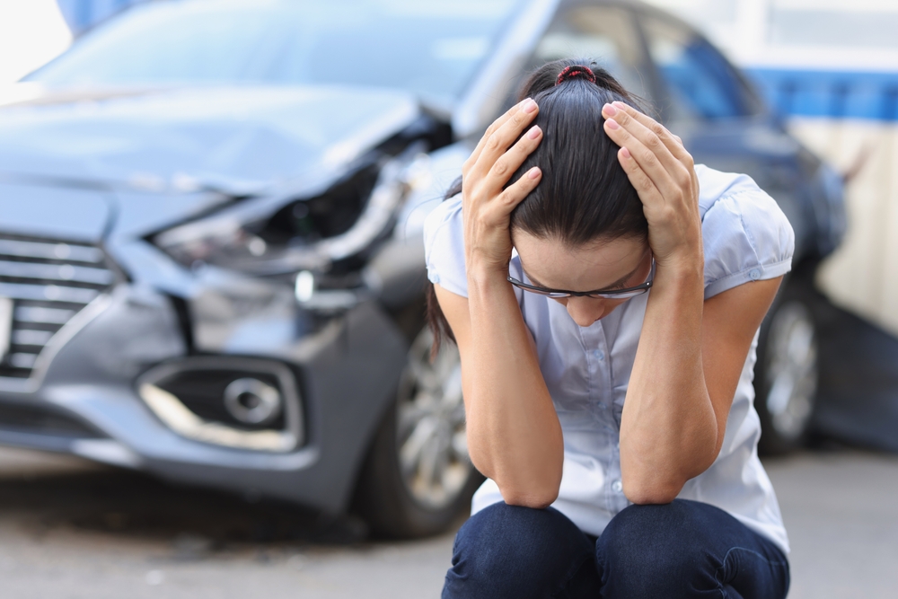 a distressed young woman holding her head after a car accident