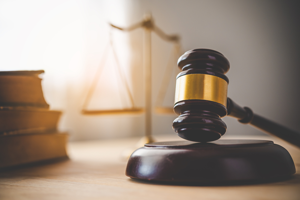 selctive focus on wooden gavel at desk with scales and law books in background