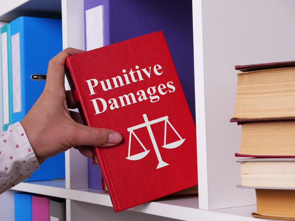 hand pulling a red book with punitive damages on it from a shelf