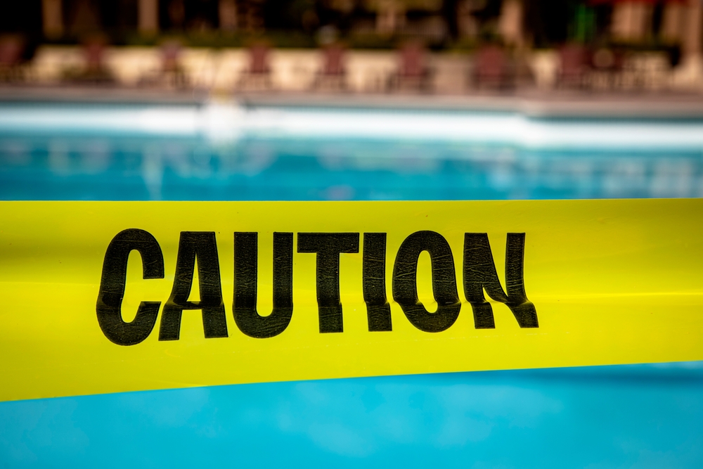 yellow caution tape at a swimming pool