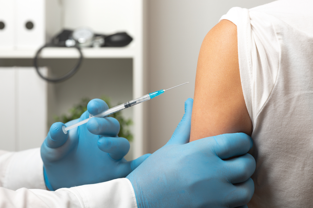 a doctor's gloved hands giving a young woman a depo-provera birth control injection in her arm.