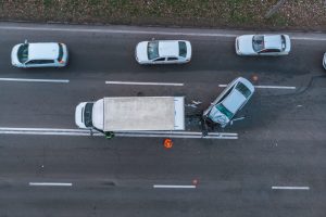 A car and truck accident on a highway with three other cars. View is from above the crash.