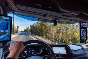 View from the driver's position of a truck on the road of the interior of the cabin with technology and screens as rearview mirrors.