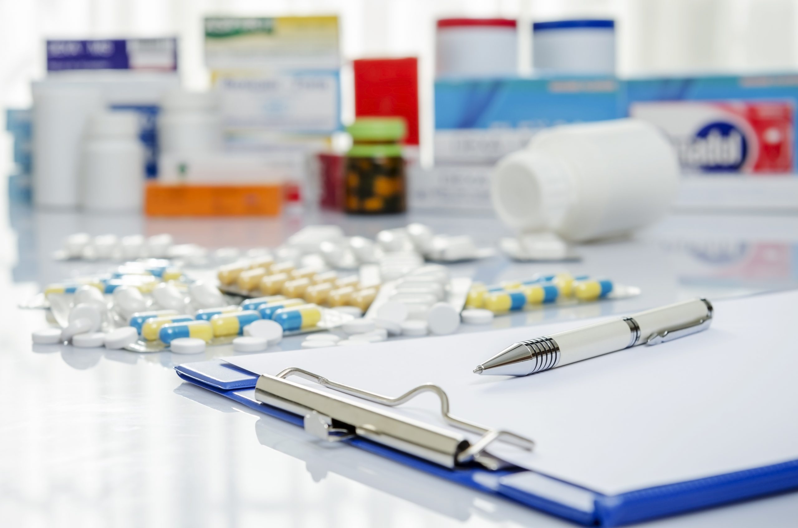 Various medication on a table next to a clipboard with medical paperwork.